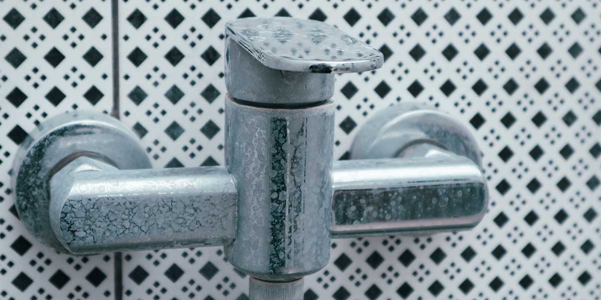 A chrome bathroom faucet covered in severe white hard water scale and mineral buildup in Sauk Rapids, Minnesota.